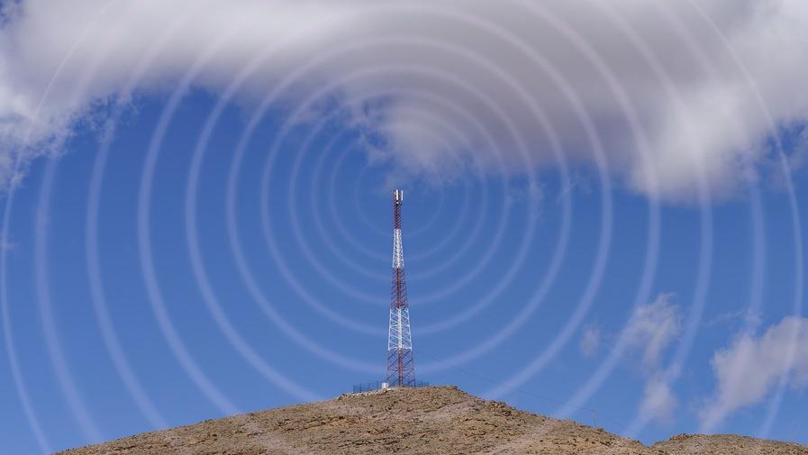 A photo of a tower on top of a mountain with a design showing connectivity.